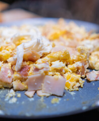 Scrambled eggs with chopped turkey ham on a round griddle