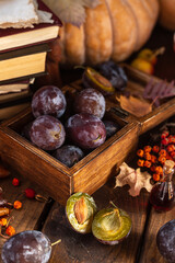 Plums in a wooden box. Two halves of a plum cut in half lie side by side.