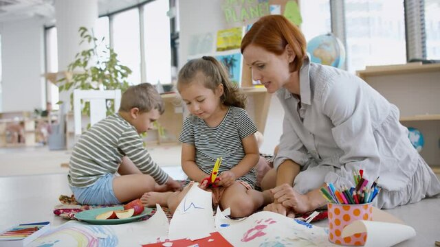 Group of small nursery school children with teacher indoors in classroom, art and craft concept.