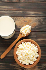 Cottage cheese with milk for breakfast in wooden bowl on brown background. Vertical photo