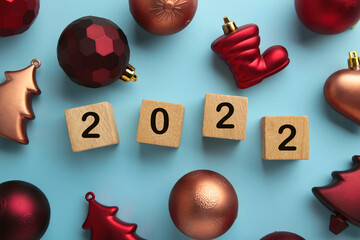 Christmas background with fir trees, fir cones and Christmas decorations and numerals 2022. New Year concept on blue.