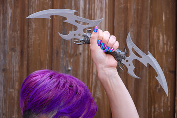 The woman raised a decorative knife over her head. Bright purple hair and blue-violet manicure. The...