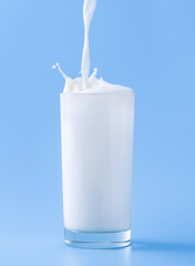 milk is poured into a glass on a blue background splash splash of milk