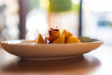 Plate of chopped mango with Mexican chamoy sauce and blurry background