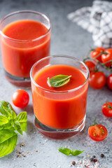 Fototapeta na wymiar Tomato juice with salt and basil on concrete background. Healthy detox tomato juice