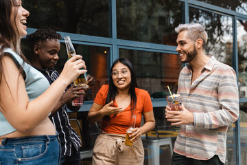 Happy diverse friends drinking cocktails at open air bar - Multiracial people, party and fun...