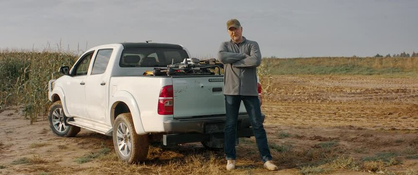 HANDHELD Male farmer posing near his pickup truck, huge agriculture drone in the back