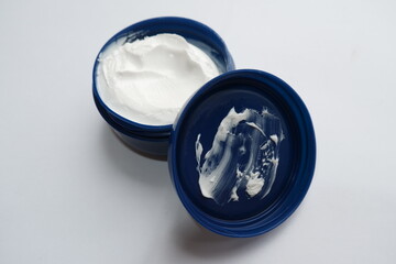 A white skin moisturizing cream in a blue container on a white background.