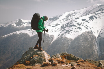 Amazing landscape with snowy mountains range and hiker with backpack on a foreground. Travel and adventure concept