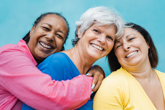 Happy diverse senior people hugging each other outdoor - Elderly friends community concept - Focus on center woman face