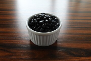 Fototapeta na wymiar Beans. Bowl with black beans on wooden table in backlight. Brazilian food.