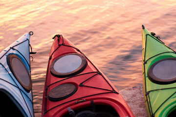 Fragments of three empty kayaks over the water of the river at winter sunrise