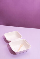 White empty package with wooden fork for bento cake. Purple background with space for text. Selective focus.