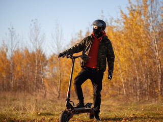 A man rides a powerful electric scooter on forest autumn roads