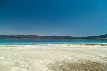 Fototapeta na wymiar Turquoise lake Salda Turkey. White mineral rich beach. Salda lake with white sand and green water. Burdur Turkey