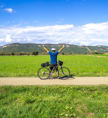 Obraz premium Adventurous cyclist man traveling in nature raises his hands as a symbol of victory. Bikepacking