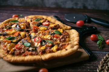 Fresh baked thin crust Italian pizza with tomato sauce pepper cheese and basil leaf on Dark rustic table background.