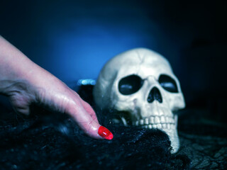 Creepy witch hand with skull on dark background