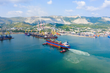 Industrial seaport Novorossiysk , top view. Port cranes and cargo ships and barges. Loading and shipment of cargo at the port. View of the sea cargo port with a bird's eye view.