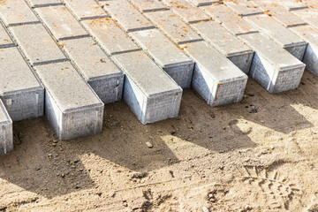 Pavement repair and laying of paving slabs on the walkway, stacked tile cubes on the background. Laying paving slabs in the pedestrian zone of the city, sand filling. Road tiles and curbs.
