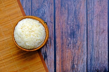 Sticky rice in bamboo wicker basket on wooden table.