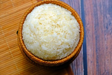 Sticky rice in bamboo wicker basket on wooden table.