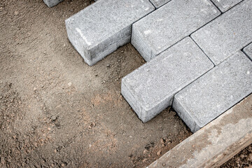 Pavement repair and laying of paving slabs on the walkway, stacked tile cubes on the background. Laying paving slabs in the pedestrian zone of the city, sand filling. Road tiles and curbs.