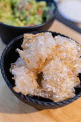 Bowls of pork rinds and guacamole on wooden surface