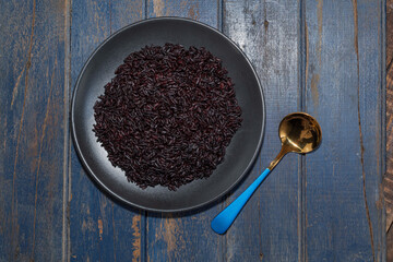 Healthy food black rice in plate on blue wood table.