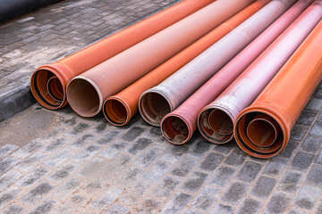 Orange sewer pipes lie on a construction site. Preparation for earthworks for the installation of an underground pipeline.