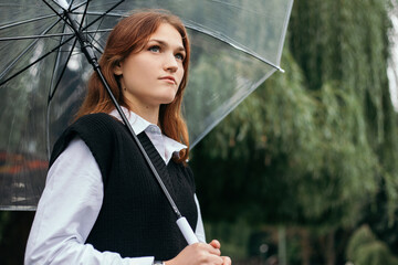 Woman hold transparent umbrella outside wet street autumn near river lake in cloud weather rain...