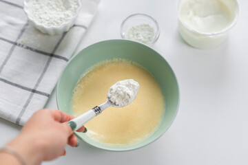 Step 4: Adding flour to the dough with sugar and butter. Step by step recipe for baking sweet plum pie. Ingredients set for cooking. Sweet pastries on white background. Culinary light background