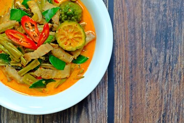 Authentic Thai red curry with pork belly and morning glory (Gaeng Tay Po) on wooden table. Thai food.