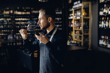 Sommelier man sniffing aroma red wine in glass background bottles restoran