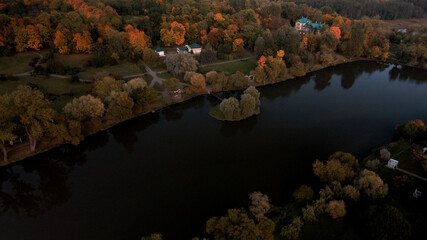 Flight over the autumn park. Trees with yellow autumn leaves are visible. Park buildings are visible. The park pond is visible. Aerial photography.