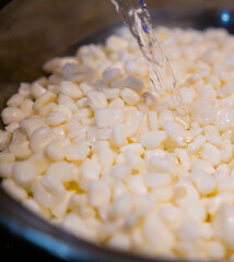 Pouring water into cooking pot with uncooked corn kernels