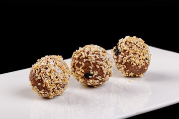 Beautiful candies with sesame seeds on a white plate on a black background