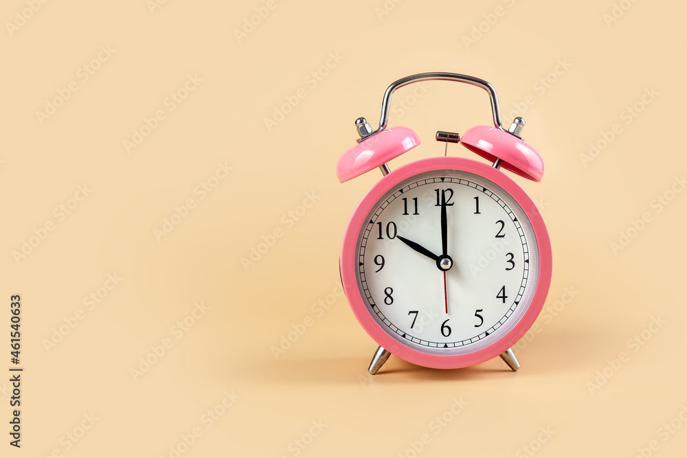 Wall mural pink alarm clock on a beige background. time concept. 10 o'clock. copy space.