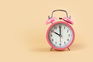 Pink alarm clock on a beige background. Time Concept. 10 o'clock. Copy space.