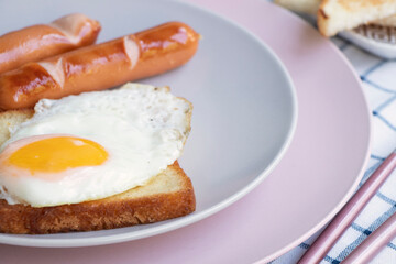 scrambled eggs, toast and sausages on a plate. slices of bread, knife and fork nearby. A healthy breakfast for one person. Breakfast cooking concept. High quality photo