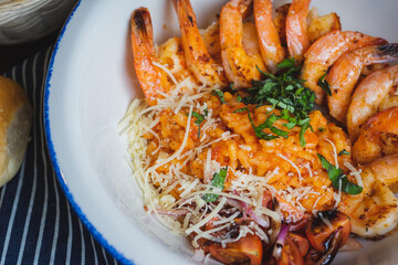 Traditional bright shrimp risotto in a bowl on a table in a restaurant with a beautiful decor in a dark key close-up.