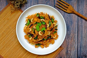 Thai sweet and sour crispy noodles (Mee Krob), crispy rice noodles in white plate on wooden table. Authentic Thai food.