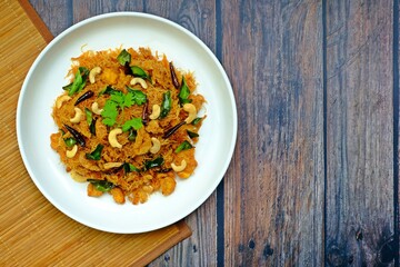 Thai sweet and sour crispy noodles (Mee Krob), crispy rice noodles in white plate on wooden table. Authentic Thai food.