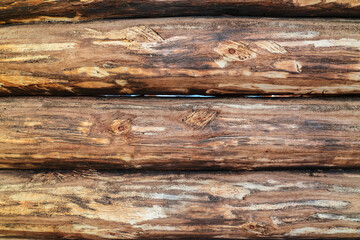 Naklejka na ściany i meble Wooden background of rough unpolished logs of a log house