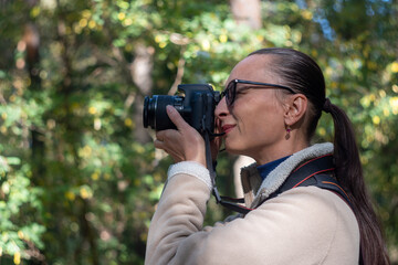 Woman photographer walking and taking picture photo of forest landscape on camera. Shooting nature.