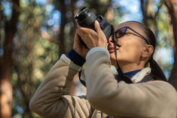 Woman photographer walking and taking picture photo of forest landscape on camera. Shooting nature.