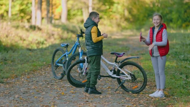 children with a bicycle are photographed on the phone in the forest