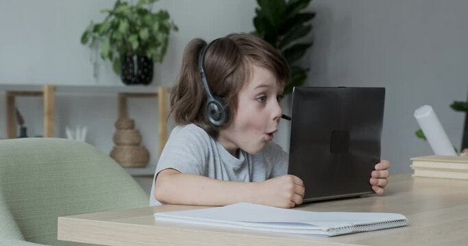 Tiny surprised overjoyed school kid won in a computer game or successfully passed an entrance exam or test The concept of online streaming, blogging, video gaming and distance education