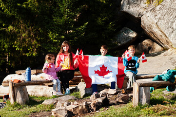 Happy Canada Day. Family of mother with three kids hold large Canadian flag celebration in...