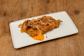 Veal schnitzel with melted cheddar cheese and crispy onion on a white tray